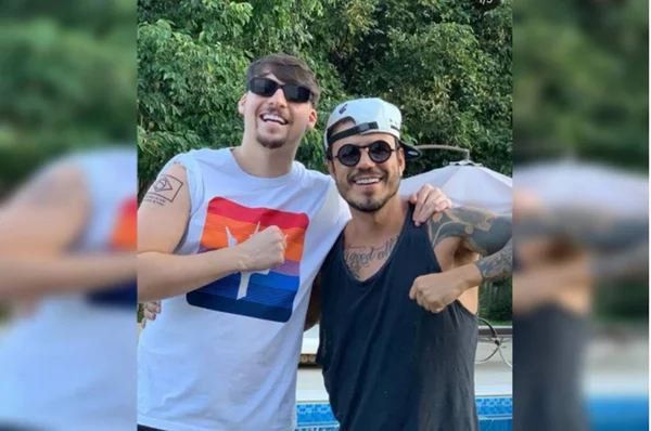 Jair Renan Bolsonaro, filho do presidente Bolsonaro, aparece de óculos escuros e regata abrançando amigo, ambos de frente para a câmera - Metrópoles