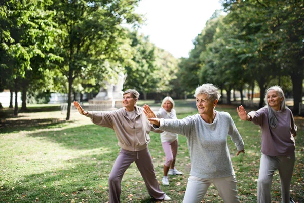 Grupo de quatro pessoas praticando tai chi ao ar livre - Metrópoles
