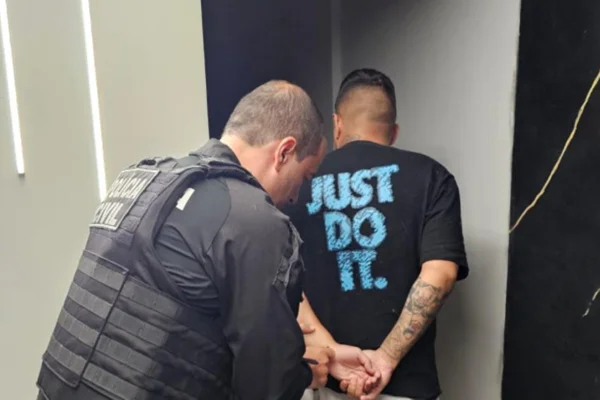 Imagem colorida de policial civil prendendo homem