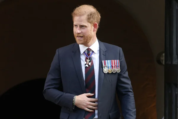 Foto colorida de homem de terno e medalhas militares. O príncipe Harry está com a mão na gravata - Metrópoles