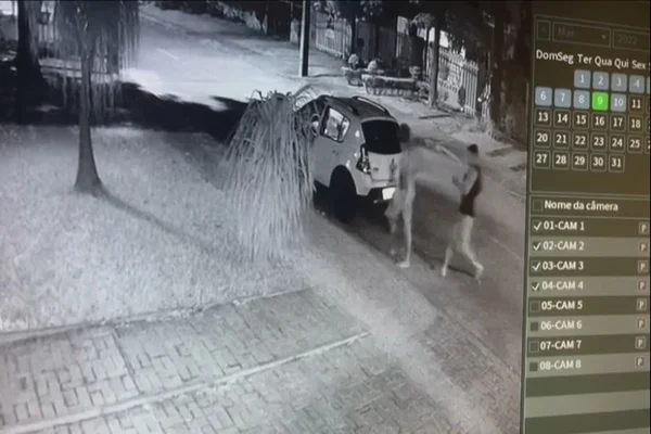 dois homens andando em direção a um carro branco estacionado