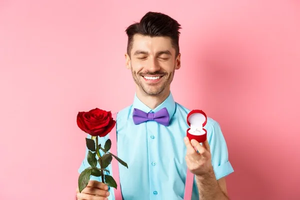 Homem com flores e aliança de casamento na mão