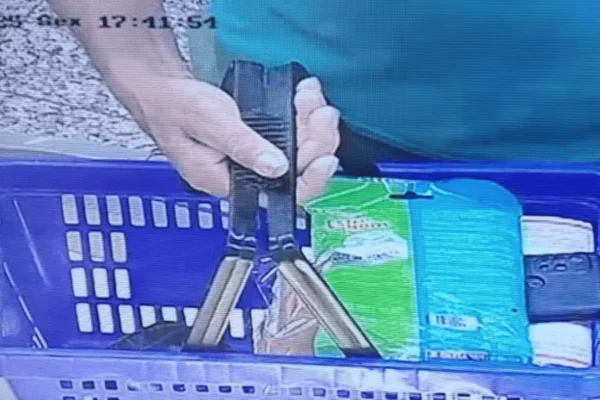 Imagem colorida de uma câmera de segurança do supermercado, que flagra o homem segurando uma cesta de compras com um celular posicionado para filmar as vítimas - Metrópoles