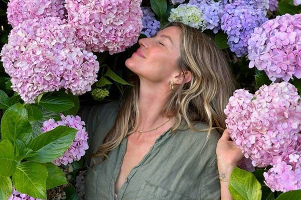 Gisele Bündchen o meio de flores rosas e roxas - metrópoles