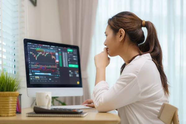 Imagem de mulher sentada diante do notebook, observando dados sobre investimentos - Metrópoles