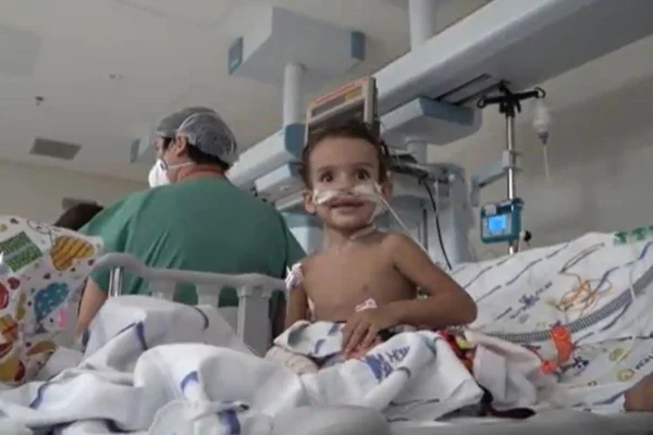 Imagem colorida de criança em cama de hospital. Metrópoles