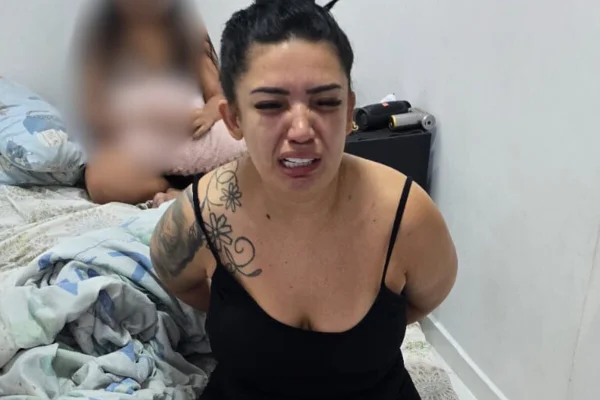 Mulher branca, de vestido preto, chora sentada sobre cama de casal - Metrópoles