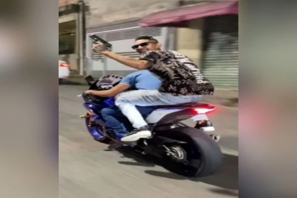 Imagem colorida mostra criminoso com arma na garupa de moto. Metrópoles