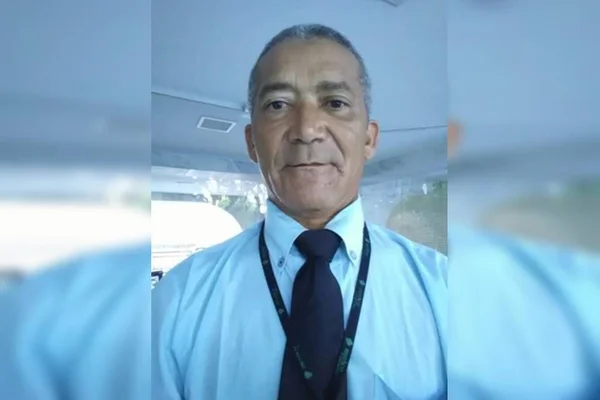Foto colorida de homem de 50 anos sorrindo para câmera de gravata e blusa social