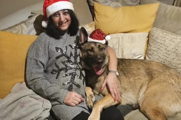Foto colorida de mulher sentada em sofá ao lado de cachorro - Metrópoles.