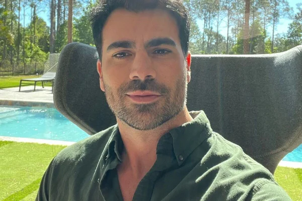Rodrigão posa com uma blusa verde e a piscina ao fundo - Metrópoles
