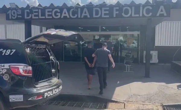 Imagem colorida de homens sendo levados para delegacia
