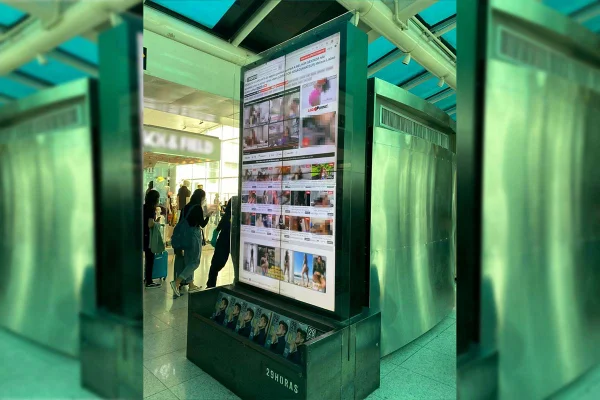 Totens de informações e autoatendimento hackeados no Santos Dumont mostram site XVideos. Ao fundo, pessoas passam - Metrópoles