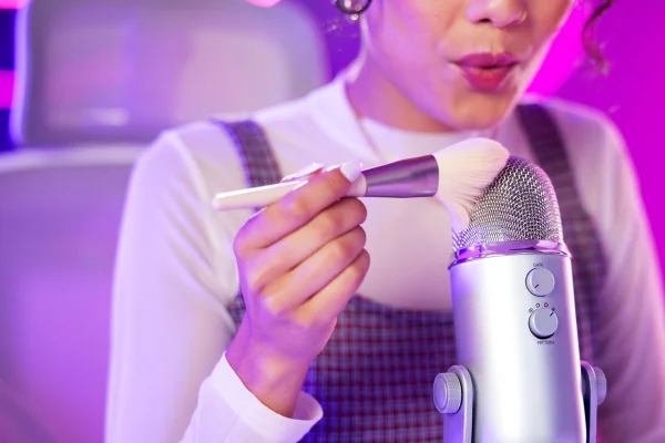 Foto de mulher passando um pincel de maquiagem no microfone - ASMR