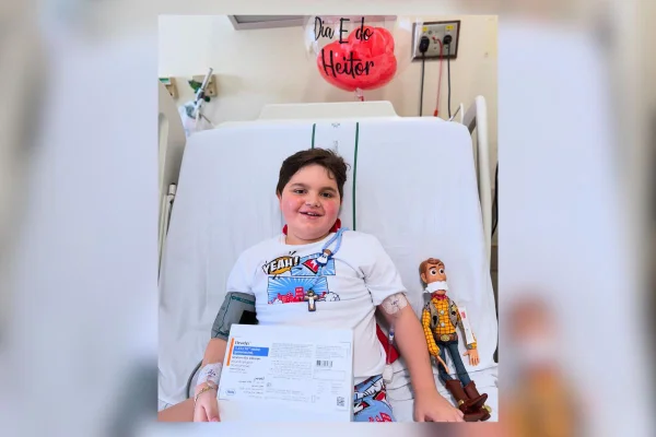Criança de 7 anos em cama de hospital, segurando a caixa do medicamento Elevydys