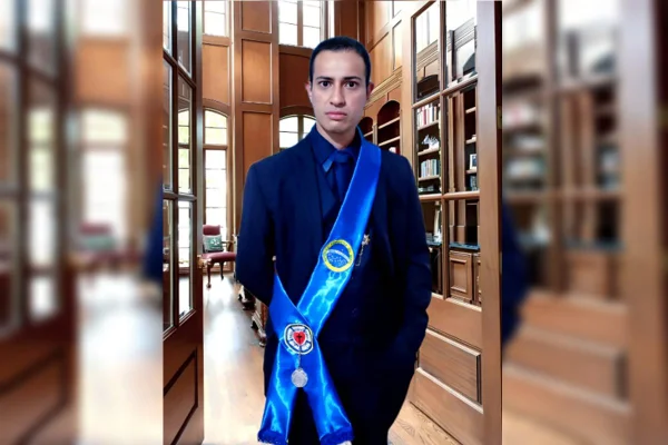 foto colorida de homem branco de cabelo curto, usando terno escuro e uma faixa azul
