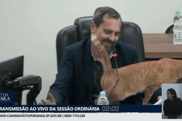 Imagem colorida de um homem com cabelos grisalhos e um gato alaranjado - Metrópoles