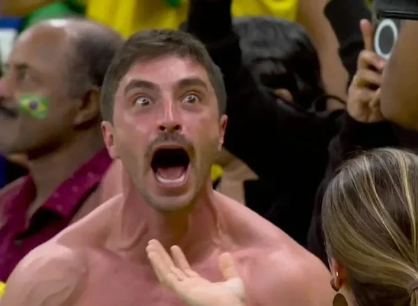 Homem branco e sem camisa gritando durante jogo do Brasil na Copa do Mundo