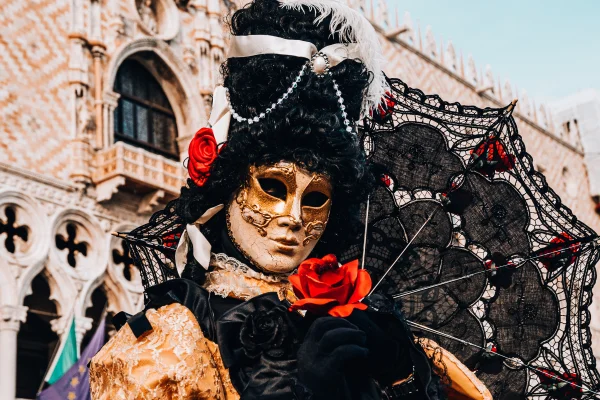 Na foto uma pessoa fantasiada em um Carnaval com uma mascara dourada