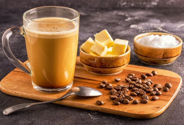 Bulletproof coffee com grãos de café sobre uma tabua com manteiga e colher por cima-Metrópoles