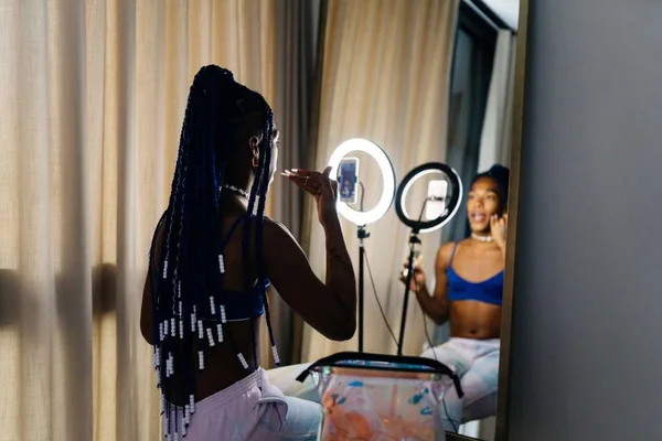 Na foto, há uma mulher passando batom e um celular à frente dela - Metrópoles