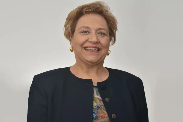 Fotografia colorida mostra Maria Auxiliadora Figueiredo sorrindo, de casaco preto - Metrópoles