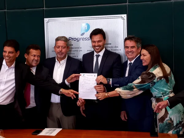Ministro das Comunicações, Fábio Faria, se filia ao PP em cerimônia na Câmara. Ele segura um papel ladeado pelo presidente da Câmara Arthur Lira e pelo ministro Ciro Nogueira - Metrópoles