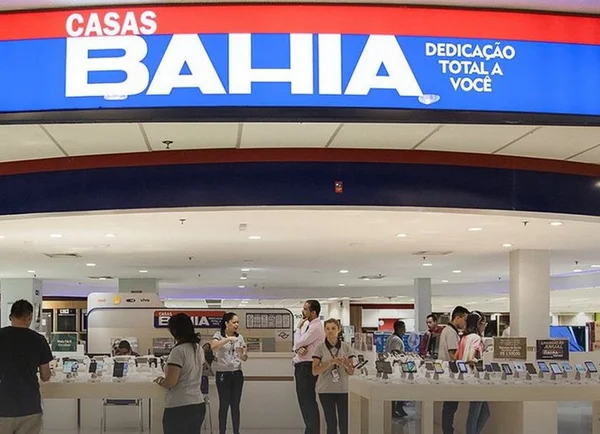 Imagem colorida de uma loja das Casas Bahia, com o logotipo no alto, ao centro, com letras brancas e fundo na cor azul. Abaixo, funcionários trabalhando na entrada da loja - Metrópoles