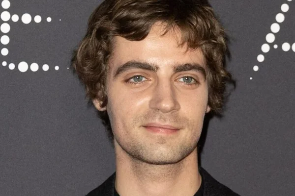 Foto de um homem branco com olhos azuis, cabelo castanho escuro e camisa preta - Metrópoles