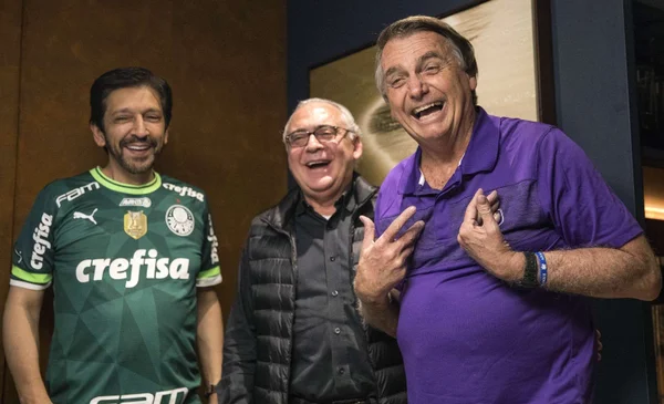 ricardo nunes de camisa do palmeiras e bolsonaro de camisa roxa. já um homem entre eles, de preto