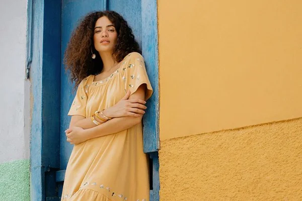 Modelo usa vestido bordado de tom terroso, em campanha da Renner