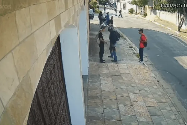 Imagem colorida de uma câmera de segurança mostra um homem de capacete assaltando alunos e roubando par de tênis - Metrópoles