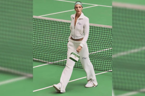 Modelo usando look branco e segurando bolsa branca com verde, da Bulgari com a Casablanca, em quadra de tênis