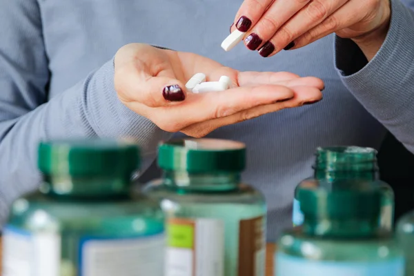 Foto colorida de mulher separando na mão suplementos em cápsulas - Suplemento para cérebro pode reduzir longevidade em homens, diz estudo - Metrópoles