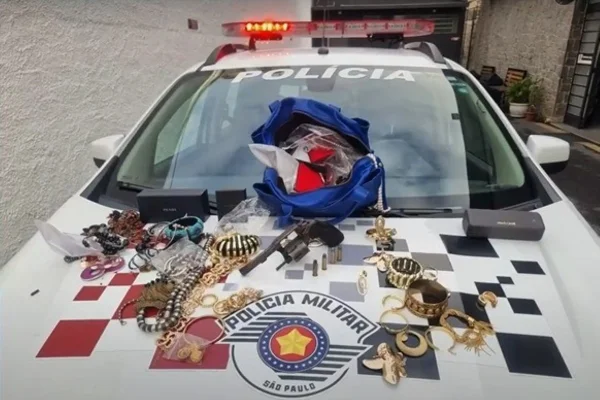 Imagem colorida de jóias expostas em carro da Polícia Militar. Metrópoles
