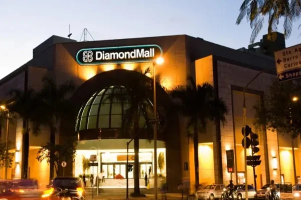Imagem da fachada de um shopping center, iluminado, no fim da tarde - Metrópoles