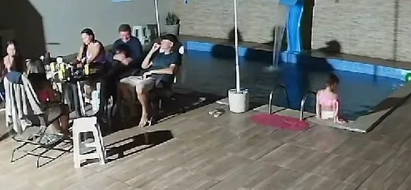 Imagem da câmera de segurança, que mostra uma familia, na beira da piscina, e a criança, brincando na borda - Metrópoles