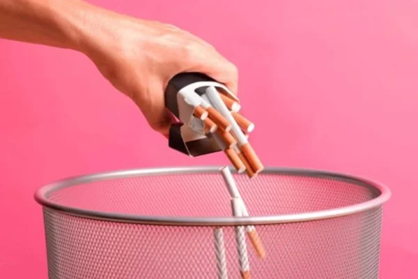 Mão despeja maço de cigarro em lixeira - Metrópoles