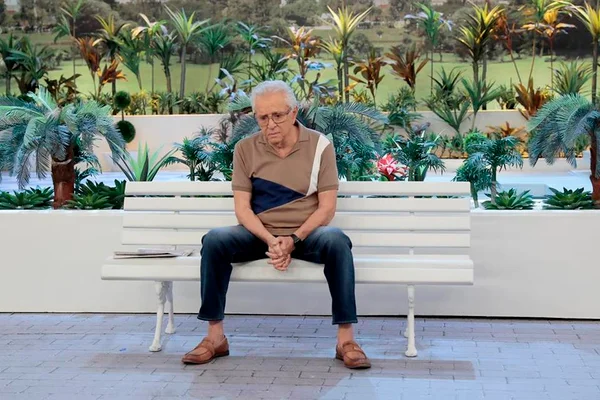 Carlos Alberto sentado triste no banco da Praça é Nossa