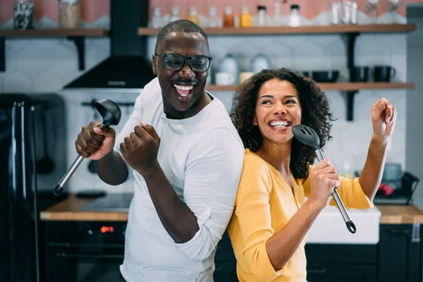 Casal dançando e cantando juntos em cozinha de casa