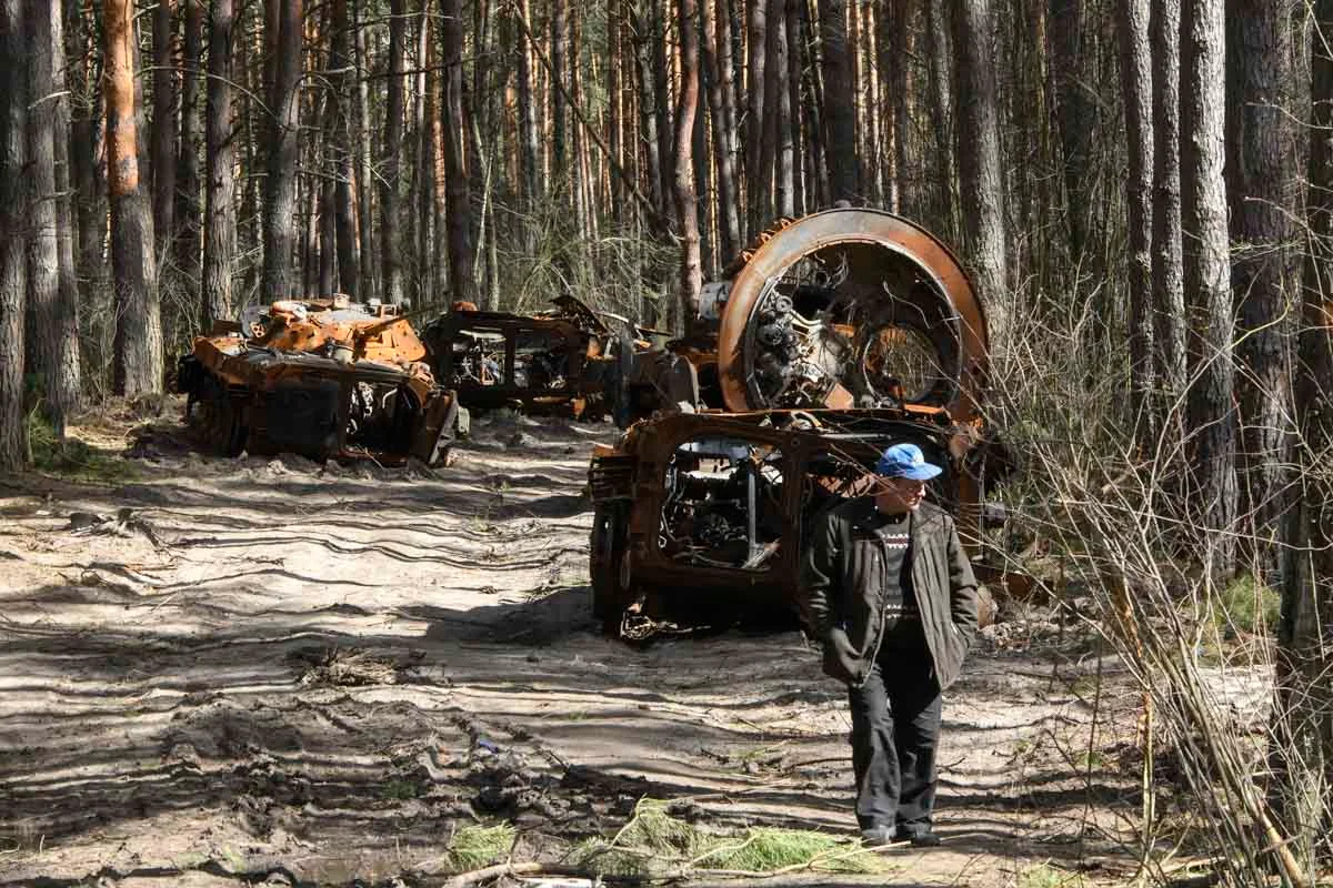 Homem passa perto de máquinas militares russas destruídas na floresta no norte de Kiev, Ucrânia Homem passa perto de máquinas militares russas destruídas na floresta no norte de Kiev, Ucrânia