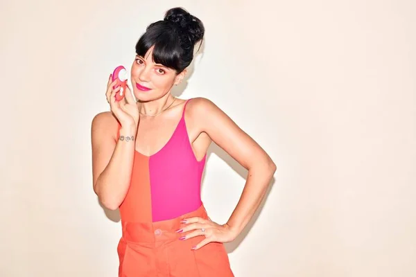 Foto colorida de Lily Allen. Ela está de blusa rosa e saia laranja, fazendo pose - Metrópoles