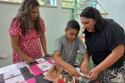 Professora auxiliar e professora de educação especial ajudam estudante com deficiência em atividade em escola estadual na Lapa