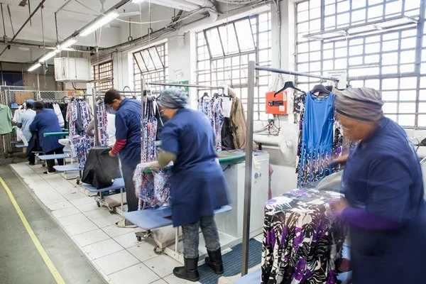 Na imagem com cor, trabalhadores da indústria da moda