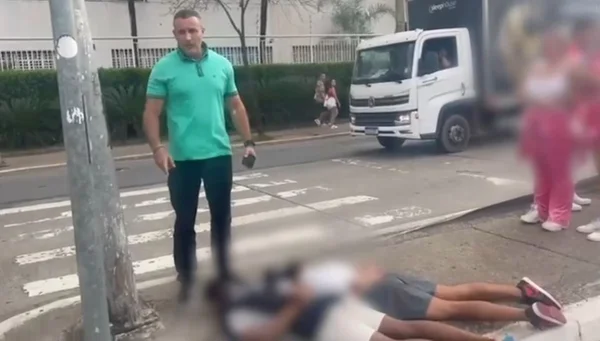 Fotografia colorida mostra o deputado Delegado Palumbo (MDB-SP), vestindo camisa verde e calça jeans, em pé, e dois homens amarrados deitados ao chão, de barriga para baixo e com os rostos ocultos em rua da Barra Funda, em SP