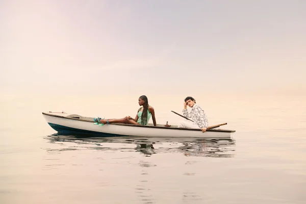 Na água, casal sentado em um barco - Metrópoles