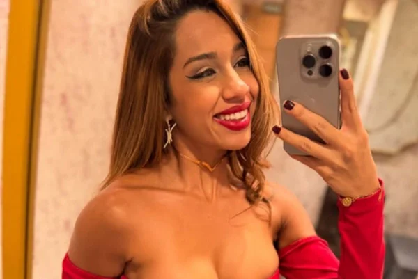 Imagens coloridas mostram mulher, morena, cabelos compridos e castanhos, vestido vermelho e decotado, fazendo selfie com celular na mão
