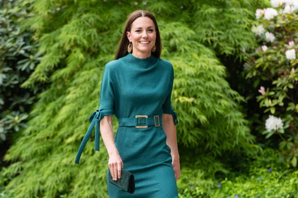 Foto colorida. Mulher com vestido verde andando