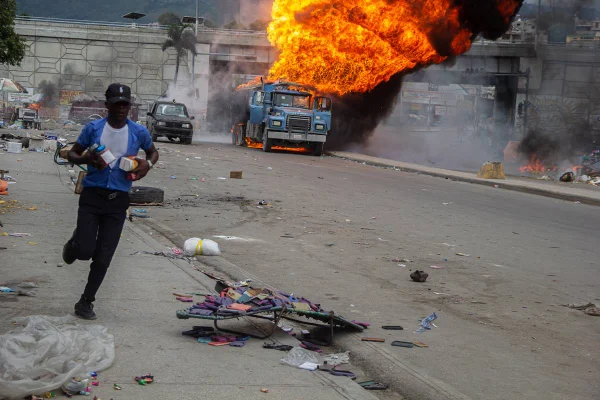 Imagem colorida mostra homem correndo em rua do Haiti - Metrópoles