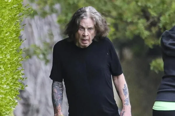 Foto de um homem branco e velho, com cabelo grisalho e preto, andando na rua, torto, de blusa preta - Metrópoles